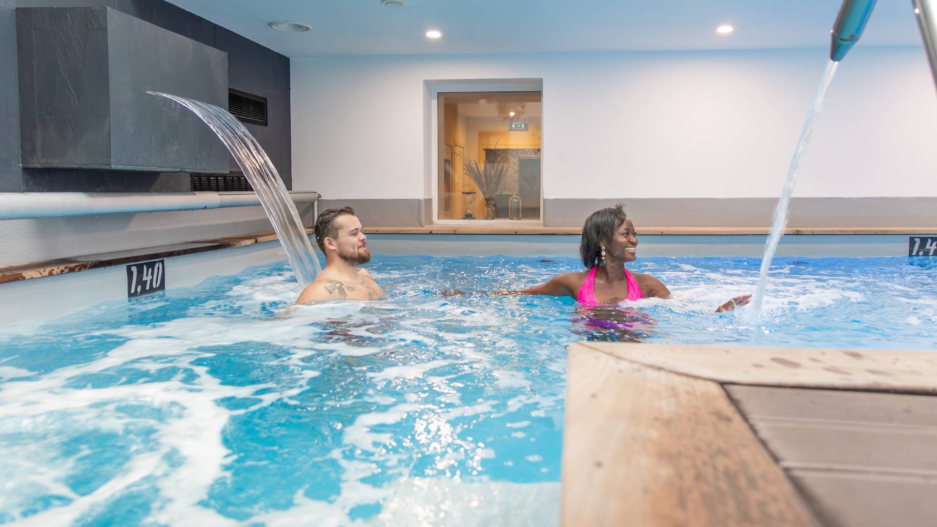 a man and a woman relaxing in an indoor swimming pool - hotel spa finistere