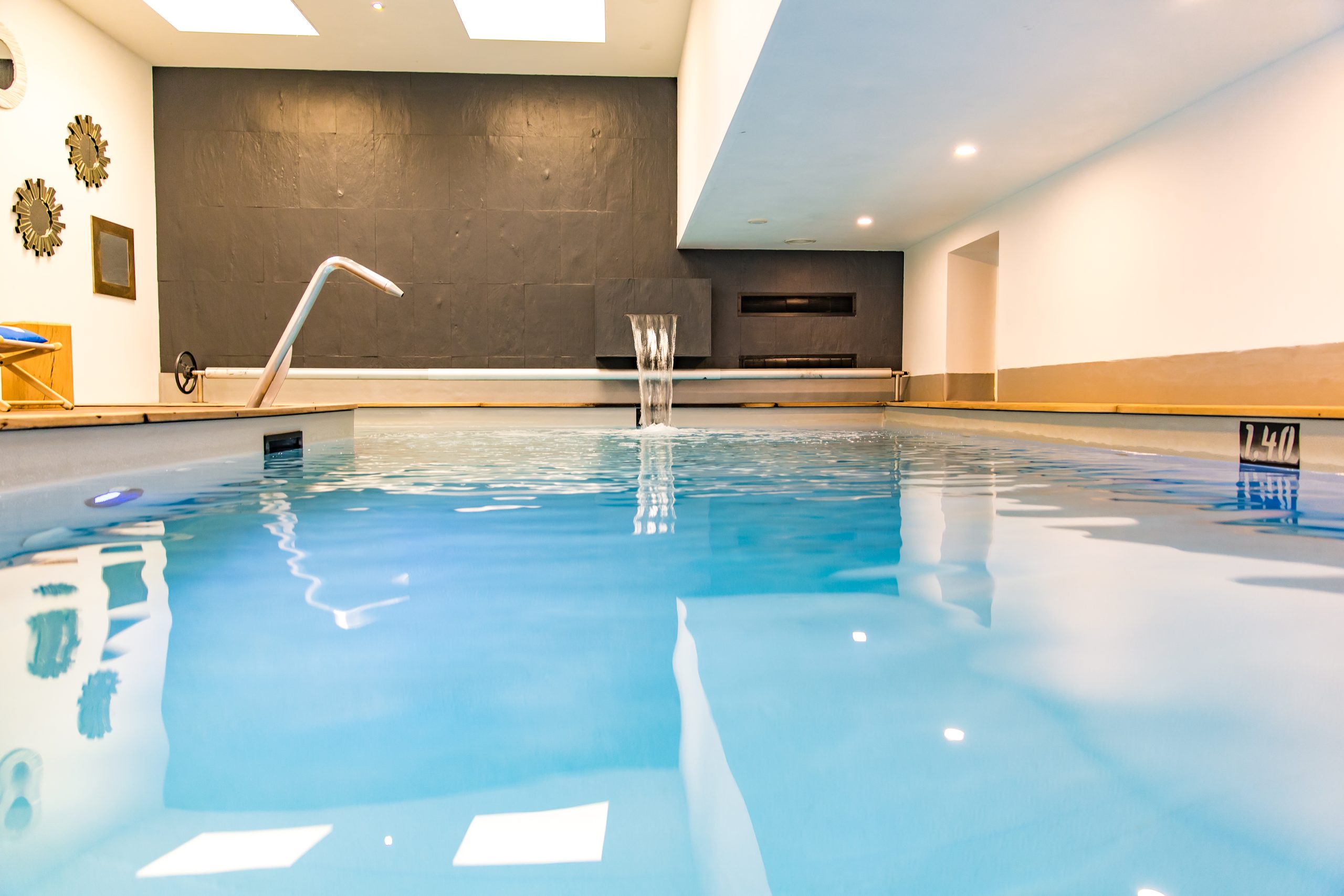 modern indoor pool with dark wall and waterfall - hotel spa finistere